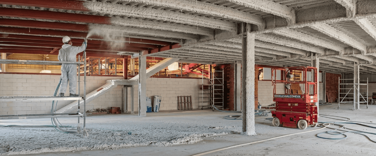Empresa de ignifugación y protección pasiva en Bilbao — equipo de aplicadores certificados de Ignifugaciones del Norte realizando tratamiento ignífugo con proyección de mortero en estructura industrial de Bizkaia